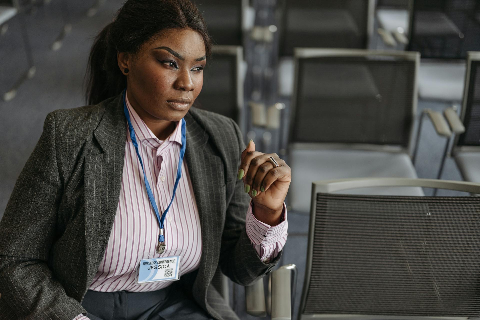 A Woman in Blazer Sitting on a Chair while Wearing a Name Tag