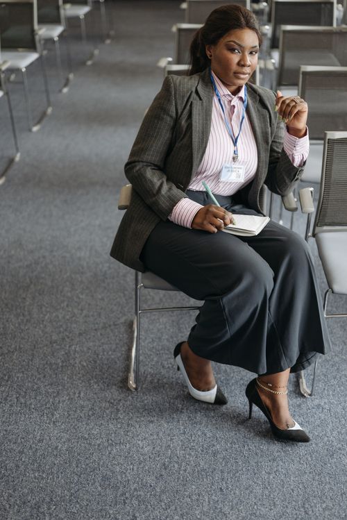 Free Professional woman attending a business meeting, seated in a conference room. Stock Photo