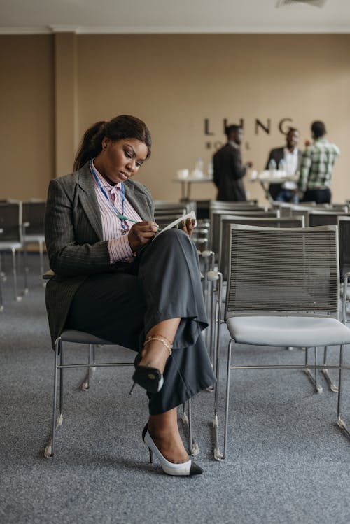 Woman in Black Blazer Sitting on Chair Writing Notes