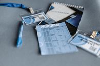 Printout Paper, Spiral Notebook, Pen and Badges on Gray Surface