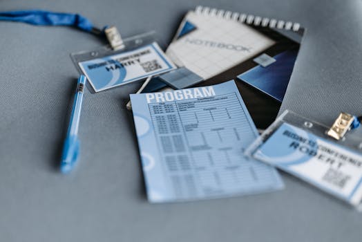 Close-up of conference materials including name tags, program, and pen on a gray surface.