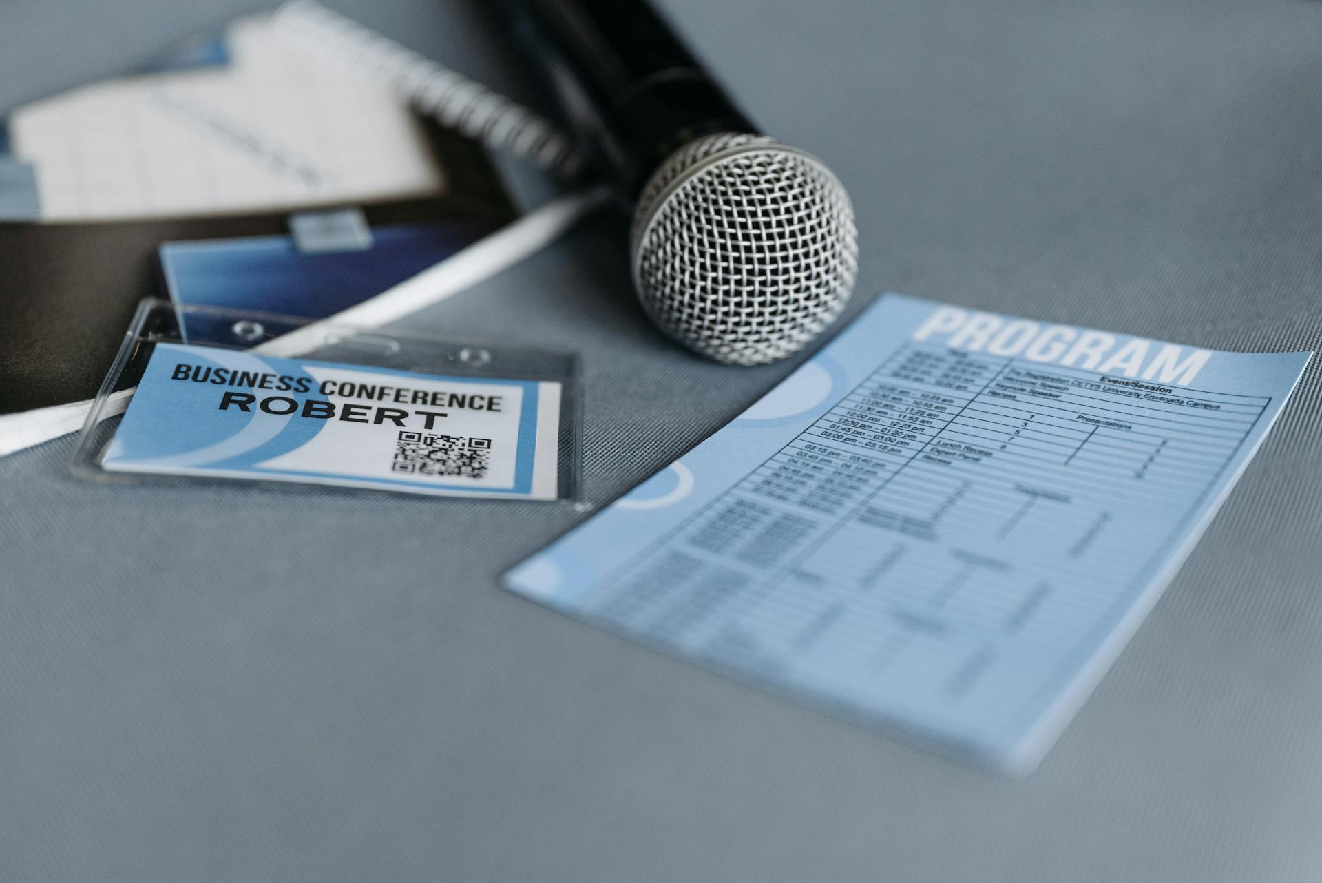 Paper Printout, Badge and a Microphone on Gray Surface