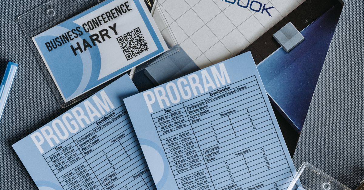 High angle shot of business conference name tags and program sheets on a gray surface.