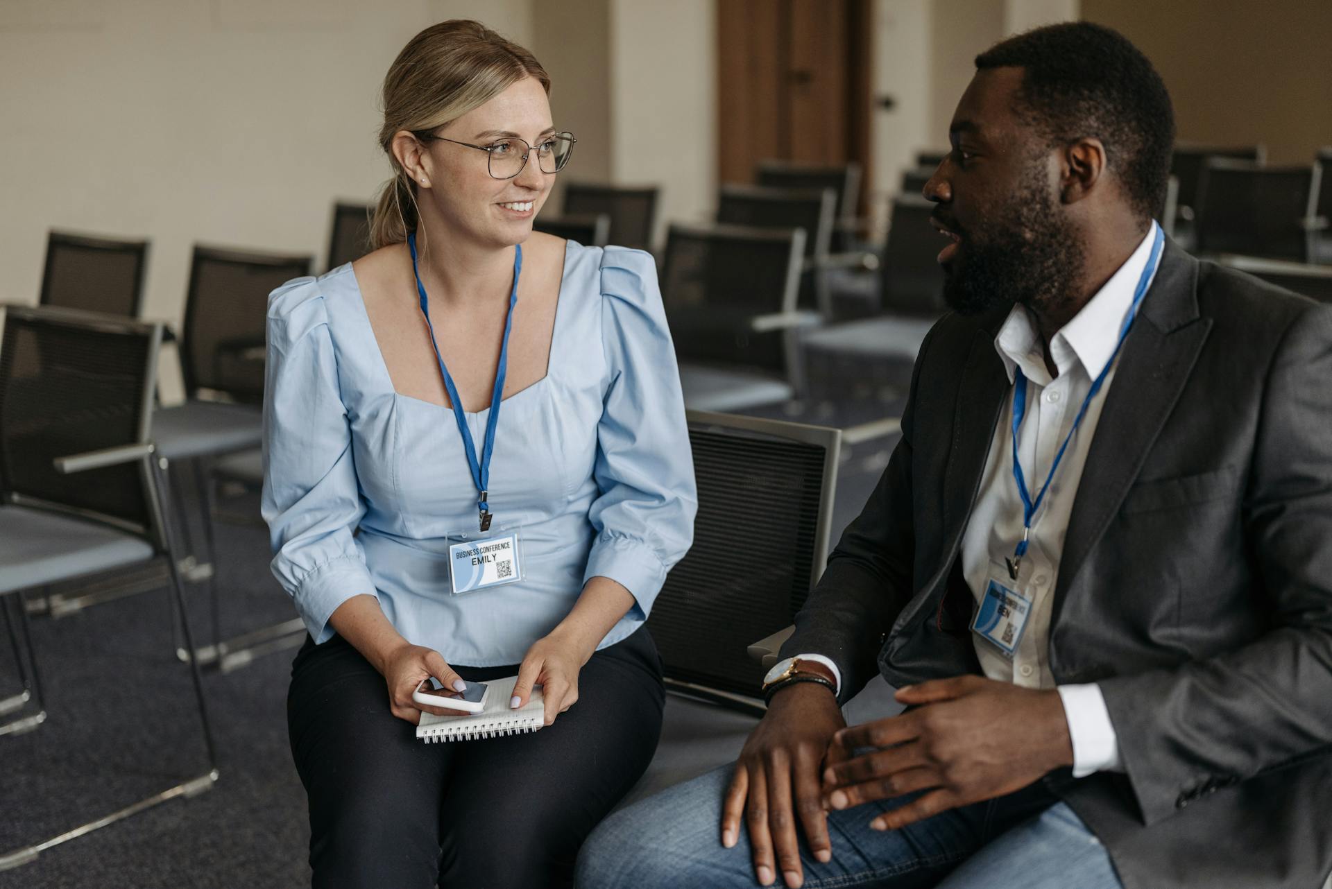 Two professionals engaged in a business discussion wearing badges and lanyards.