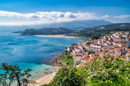 Free Captivating aerial view of a charming coastal village by the sea with mountains in the background. Stock Photo