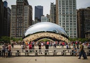在千禧公园的热门旅游景点芝加哥云门周围，人们聚集在一起欣赏城市景观的倒影