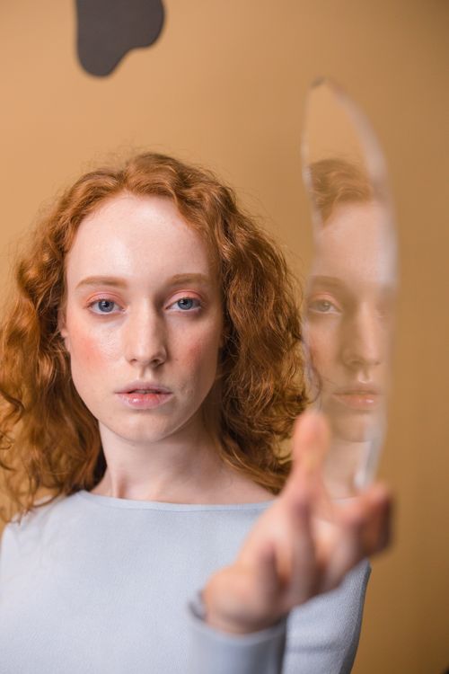 Free Portrait of a woman holding a mirror with a reflection capturing unique angles. Stock Photo