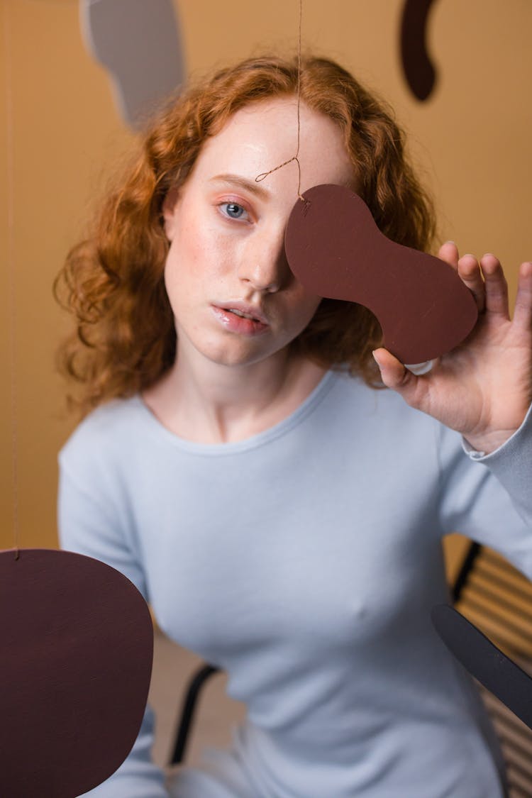 A Woman Holding An Object While Covering Her Eye