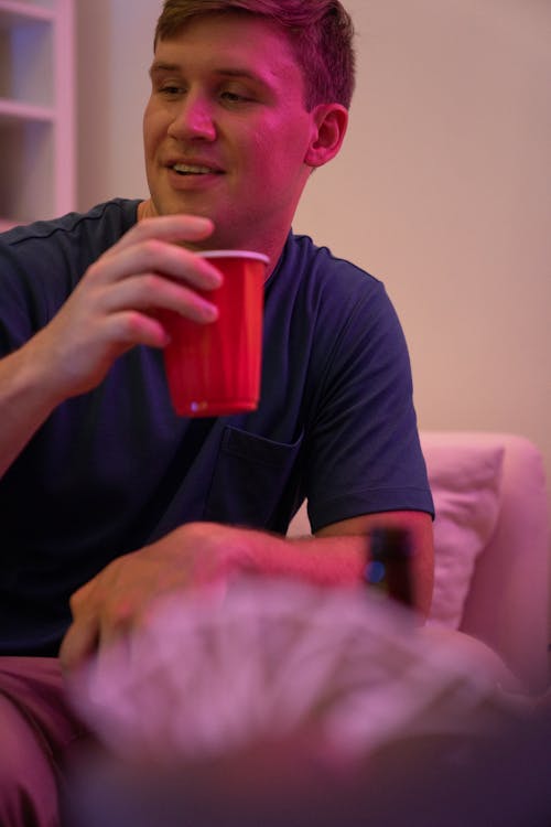 A Man in Blue Shirt Holding a Red Cup