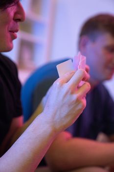Two friends enjoying a card game at an indoor gathering under soft lighting.