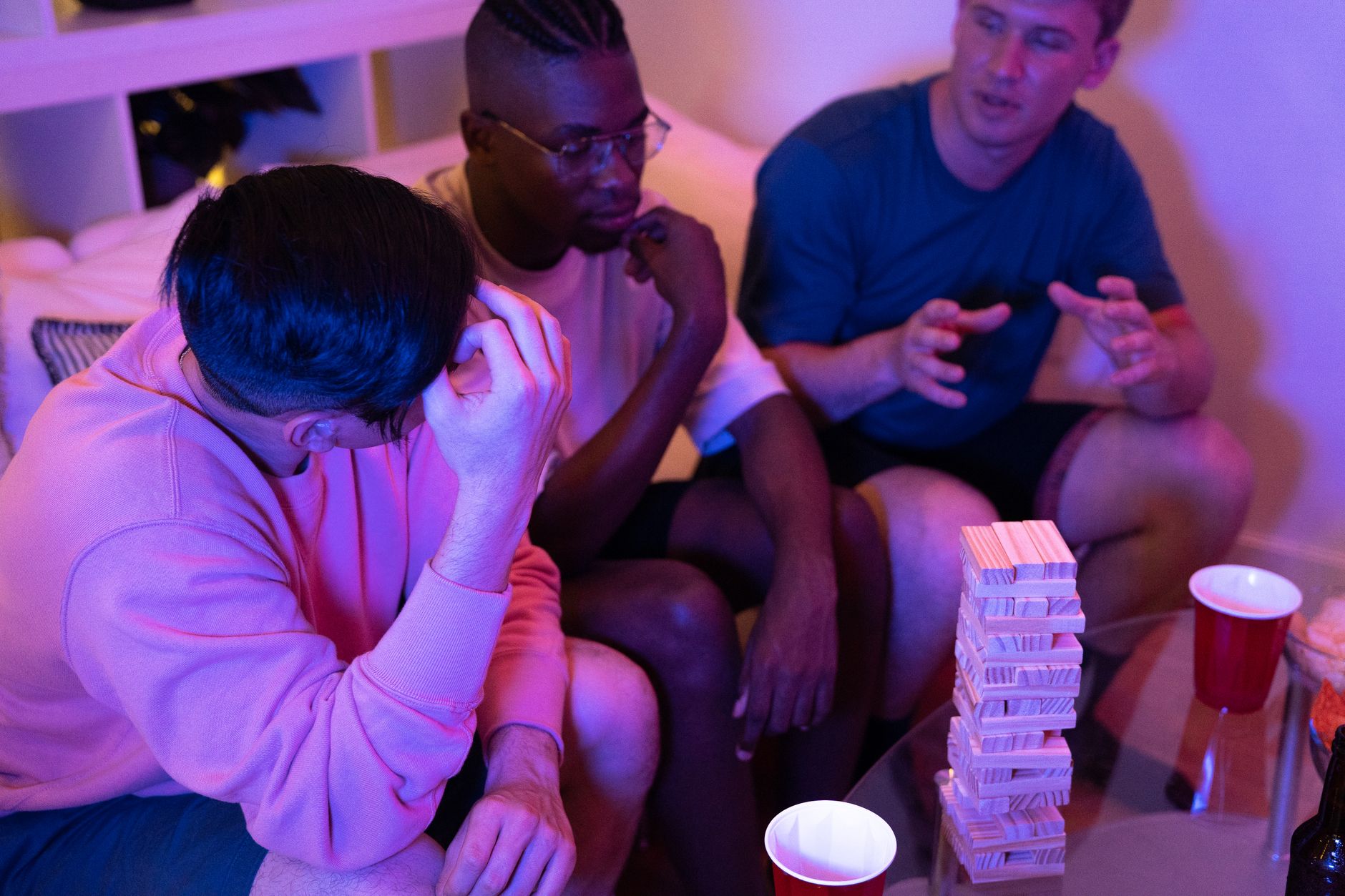 Three friends engaged in a game of Jenga, highlighting fun and camaraderie indoors.