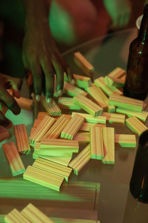 Free A lively scene of people playing Jenga on a table, accompanied by beer bottles. Stock Photo