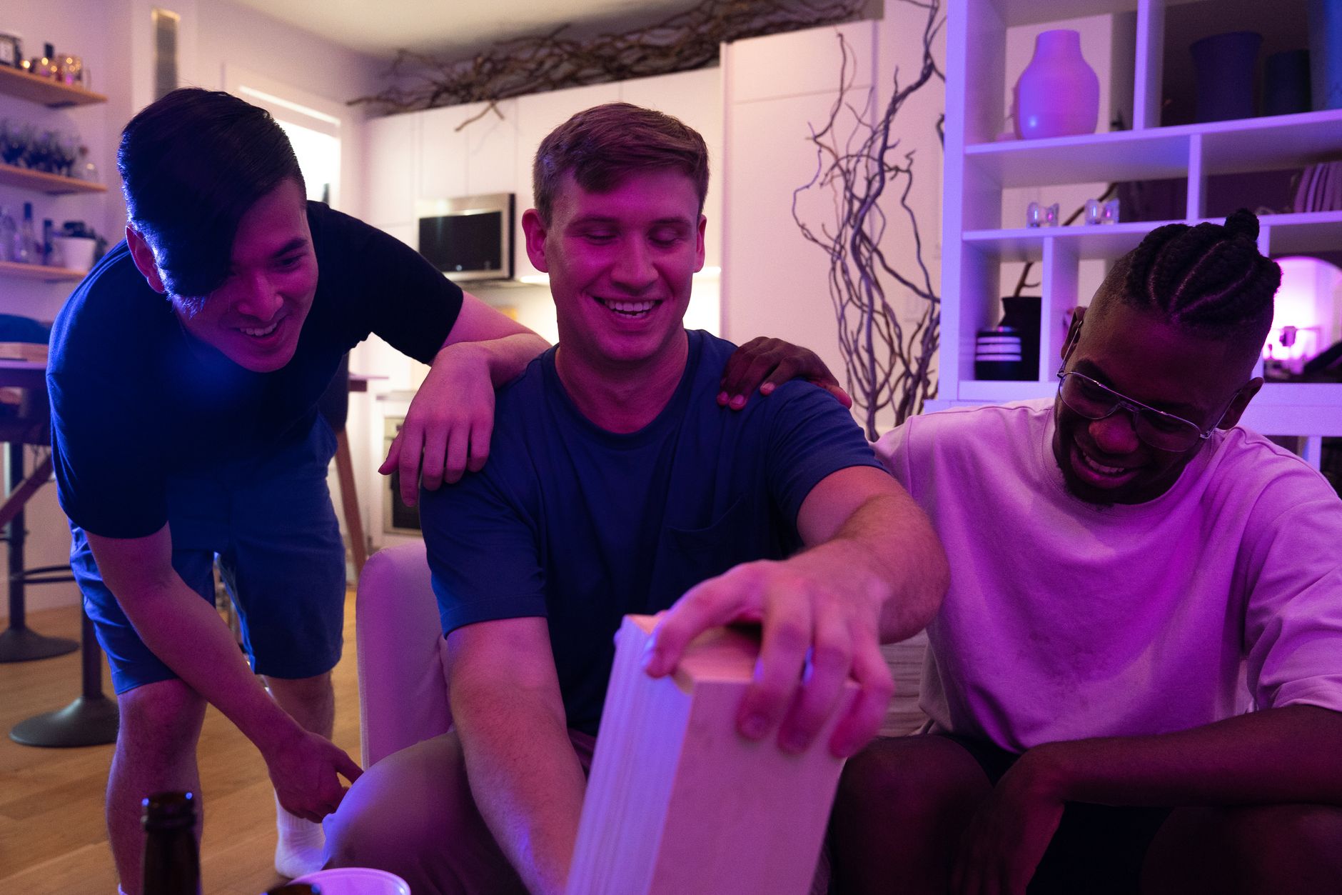 Three friends enjoying a fun game night together indoors with laughter and smiles.
