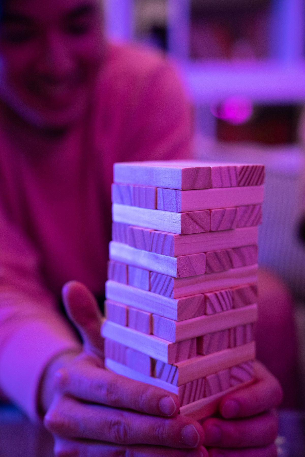 A person holding a stacked Jenga tower on a table