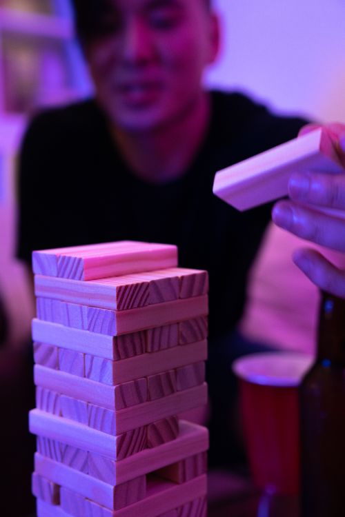 Free Close-up of hand playing a wooden block stacking game during a fun night indoors. Stock Photo