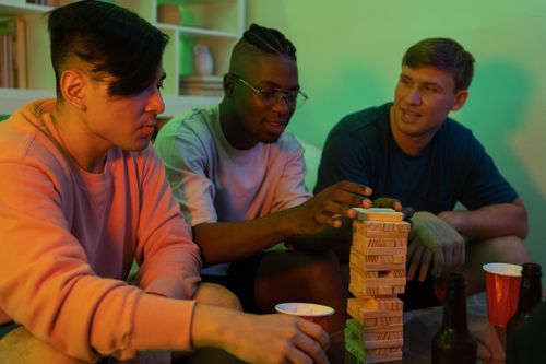Free Three men playing Jenga together indoors. Fun and leisure in a cozy setting. Stock Photo