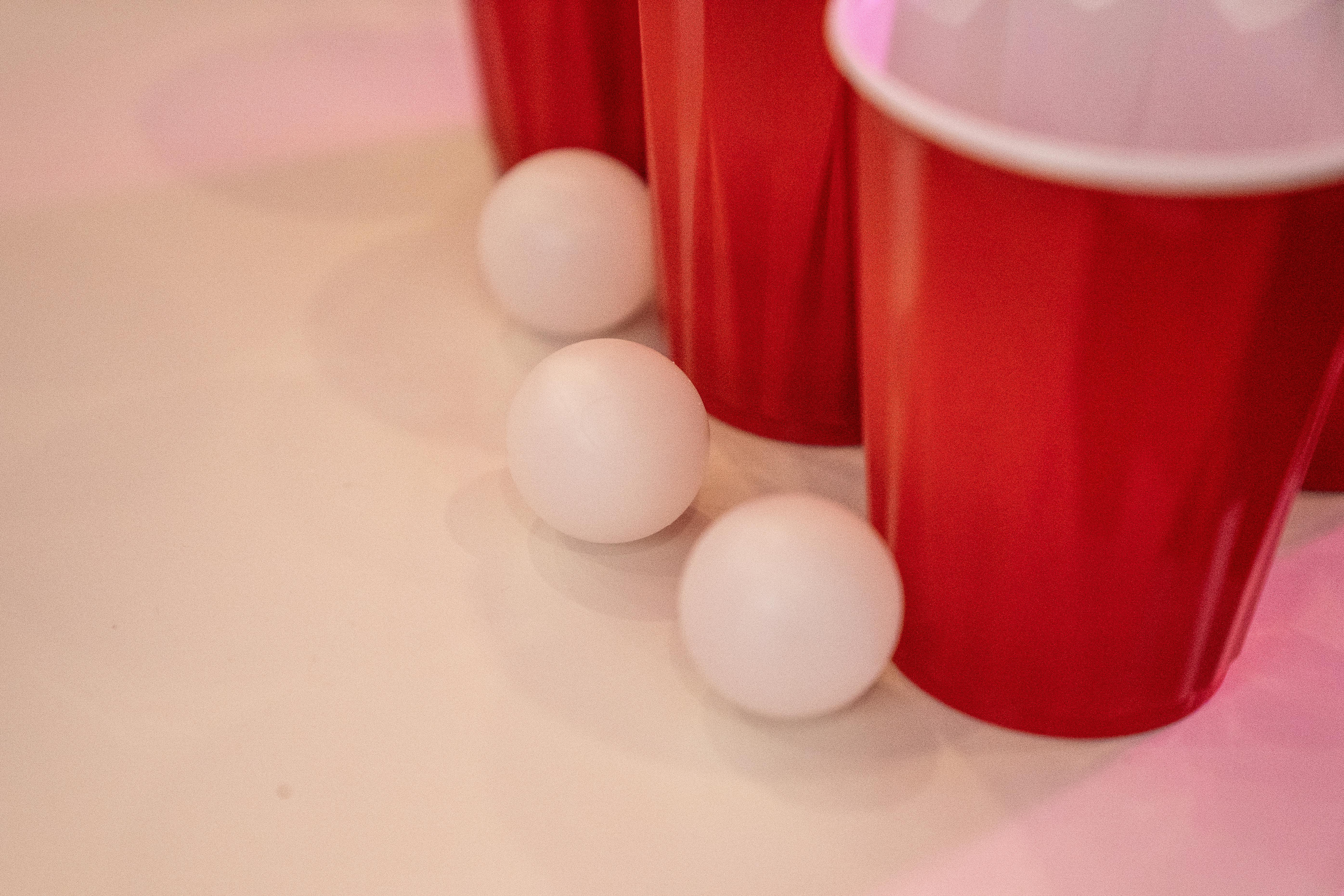 Red Cups Beside Small Balls on a White Surface · Free Stock Photo