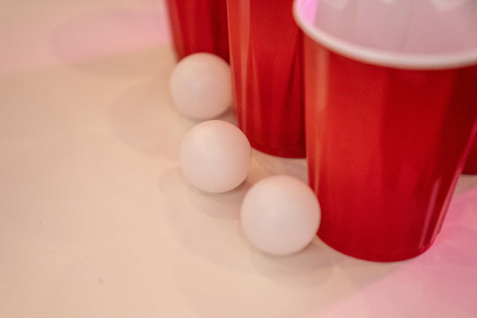 Red Cups Beside Small Balls on a White Surface