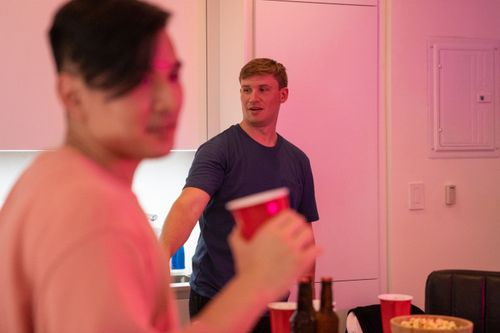Free Two friends enjoying a casual indoor party with drinks and popcorn. Stock Photo