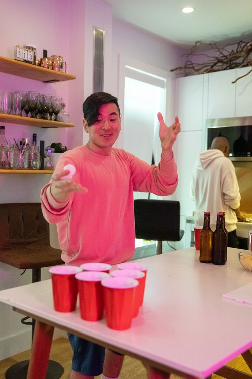 Free Two friends play beer pong at home with drinks on the table. Stock Photo