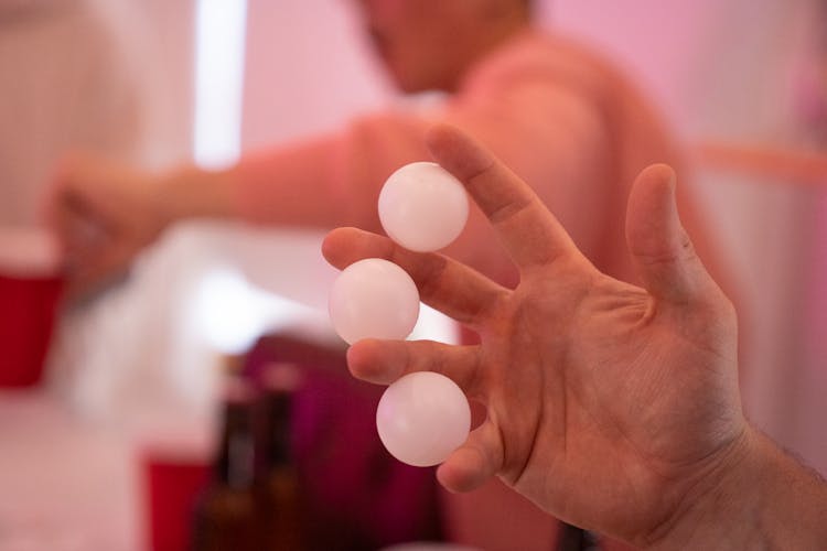 A Person With Ping Pong Balls In Between Fingers