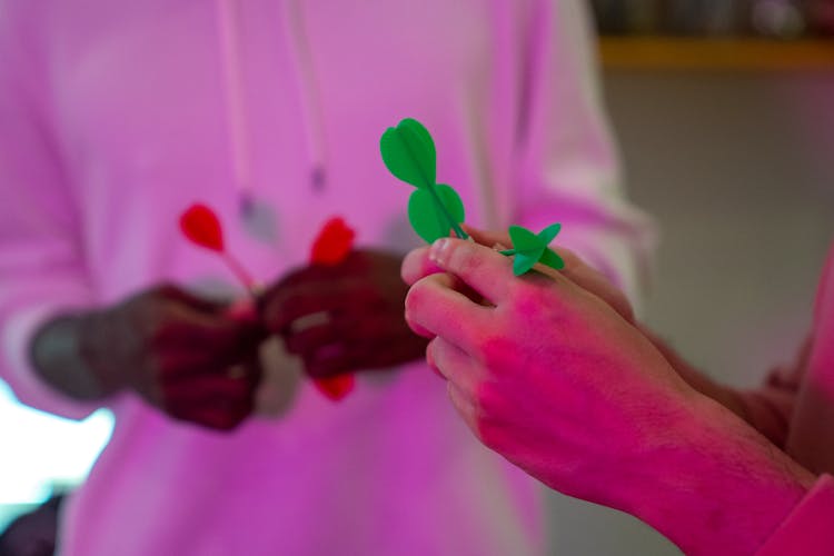 A Close-Up Shot Of People Holding Darts