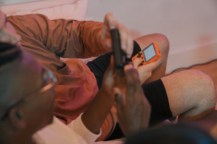 Men Sitting On The Couch And Playing On A Retro Game Console 