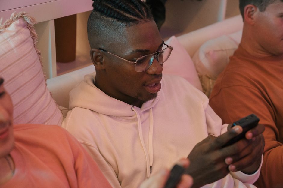 Group of friends enjoying leisure time, browsing on smartphones indoors.