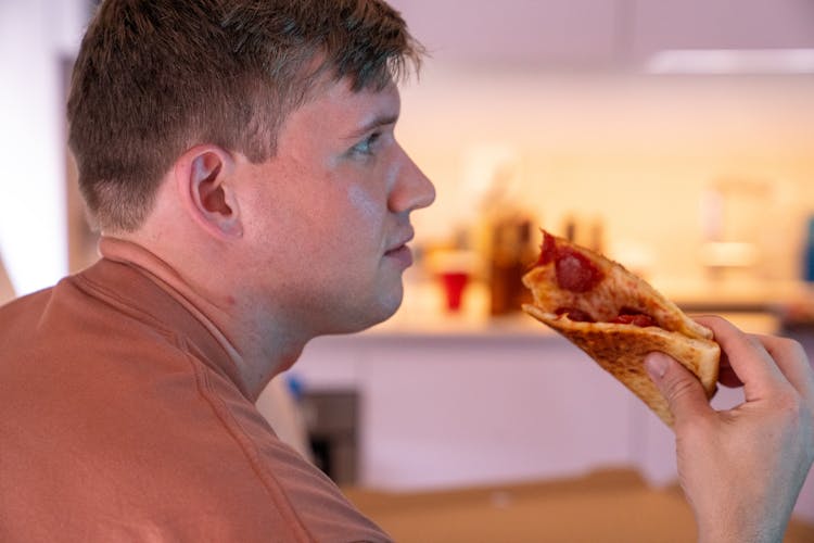 Close-Up Shot Of A Man Holding A Slice Of Pizza