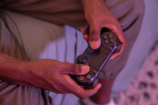 Hands gripping a game controller, engaged in a video game indoors.