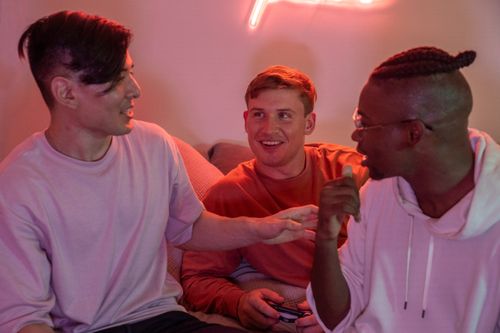 Free Three friends enjoying a lively conversation on the couch at home. Stock Photo