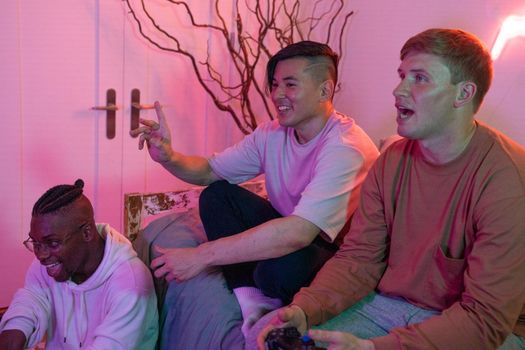 Three young men enjoying a gaming night with controllers and a relaxed ambiance.