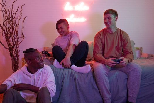 Three diverse friends joyfully playing video games together in a cozy room setting.