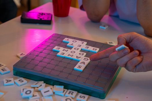 Close-up of a Scrabble game in progress, highlighting words and player interaction.