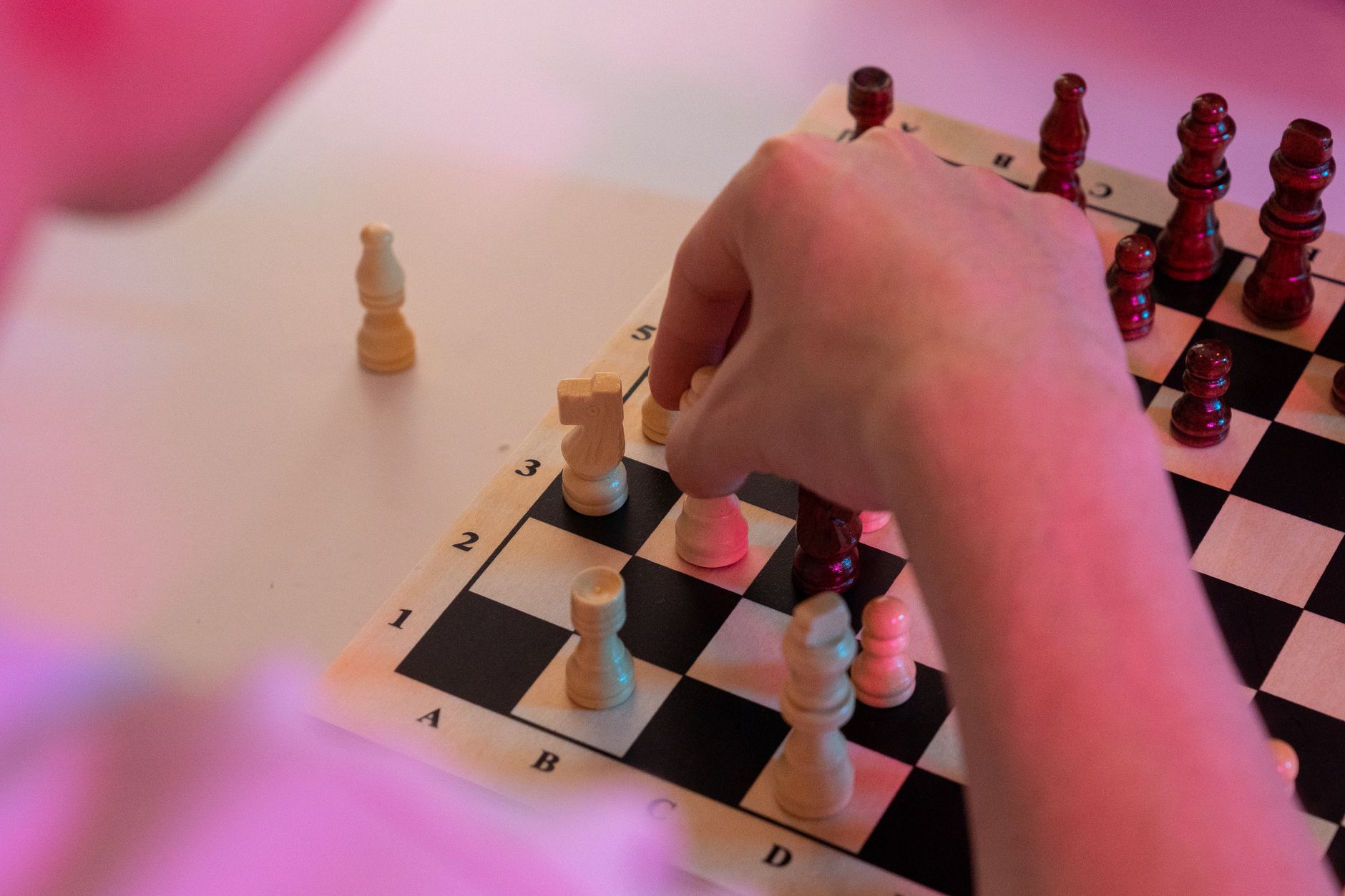 Close-up of a hand making a strategic move on a chessboard, highlighting game intensity.
