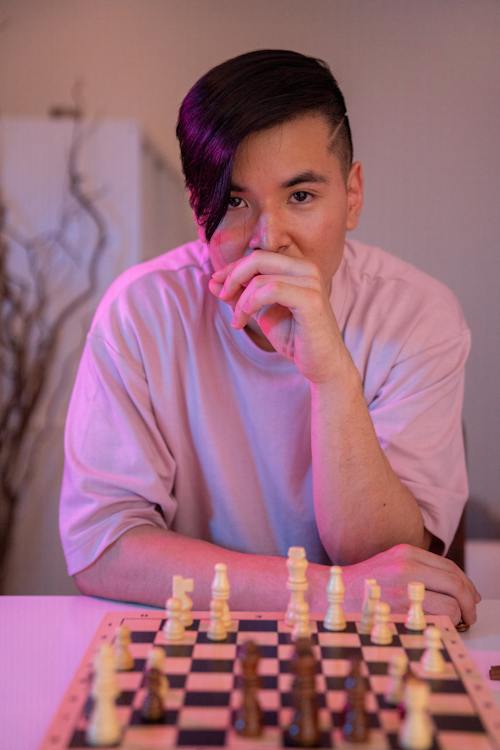 A Man Sitting in front of a Chessboard with His Hand on Face