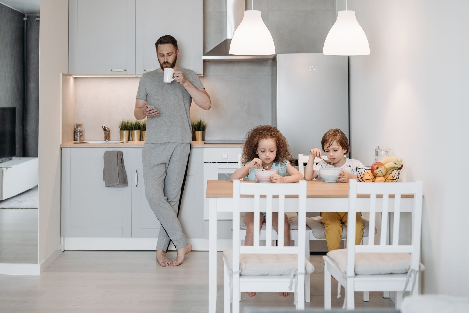 A Man Standing Beside His Kids while Using His Mobile Phone