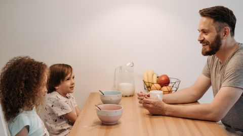 A father having a warm conversation with his children during breakfast at home.
