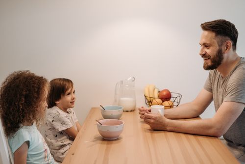 Free A father having a warm conversation with his children during breakfast at home. Stock Photo