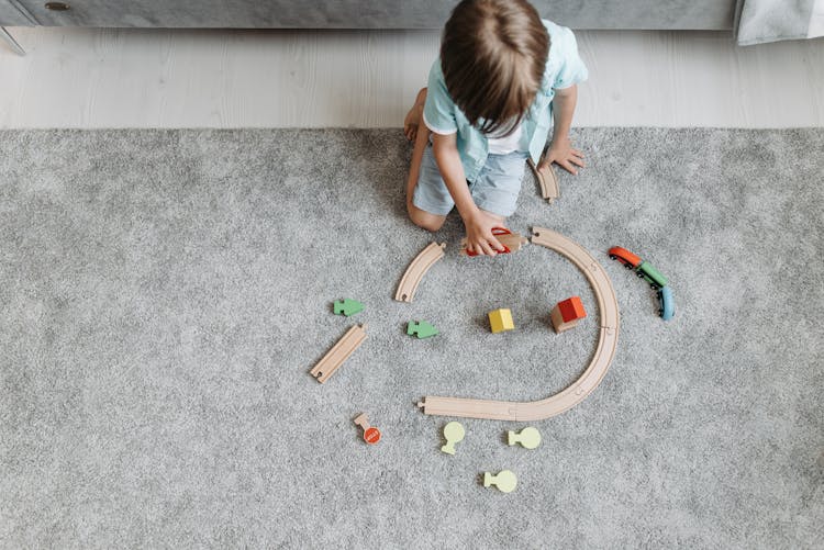 A Boy Playing With A Toy Train Track