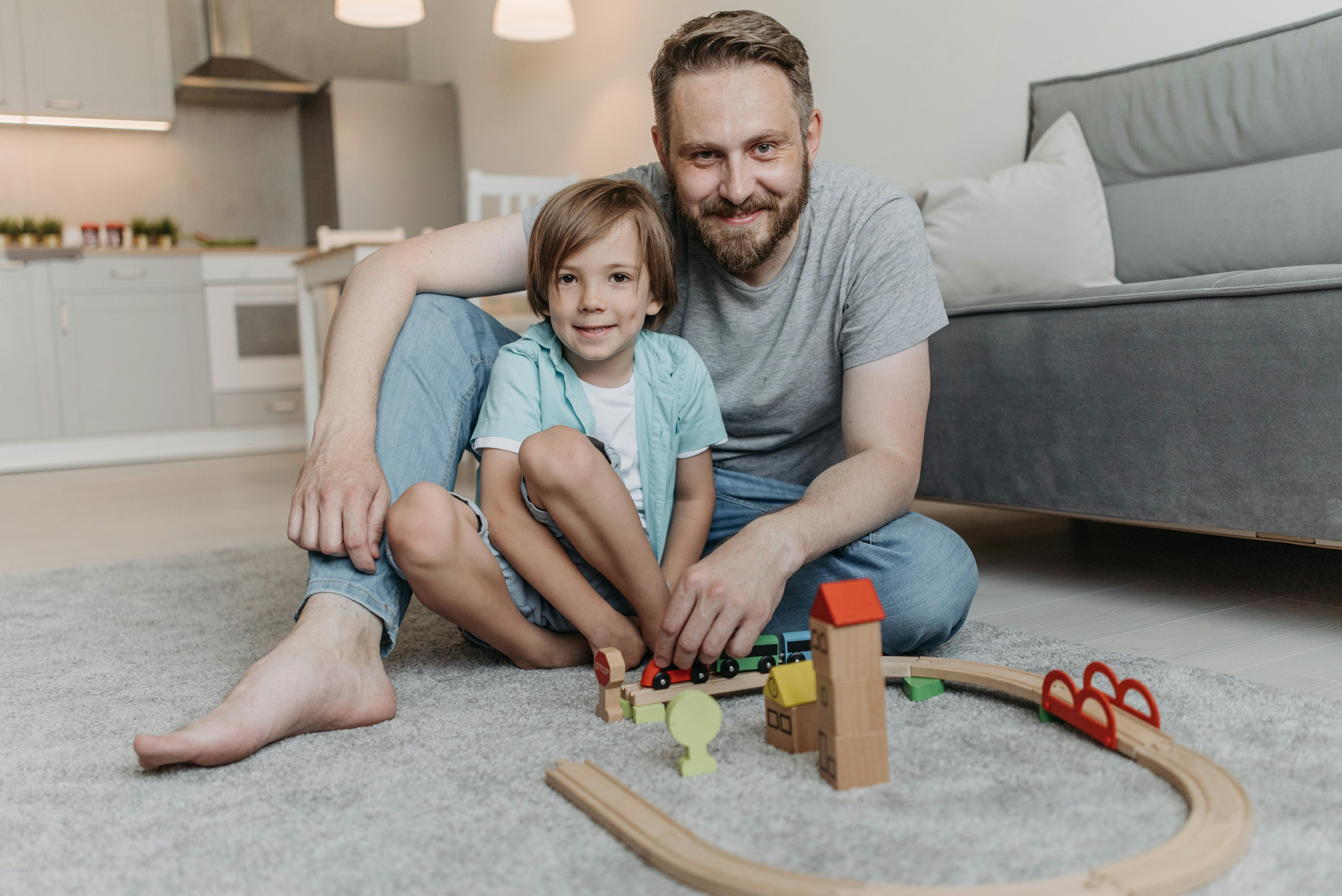 Father and son playing with toy train set in a cozy living room, enjoying quality bonding time.