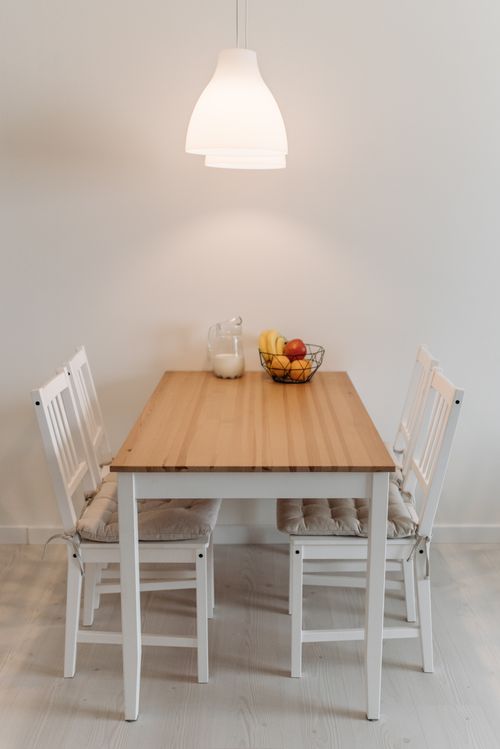Free A cozy minimalist dining room with a wooden table and pendant light, featuring simple decor. Stock Photo