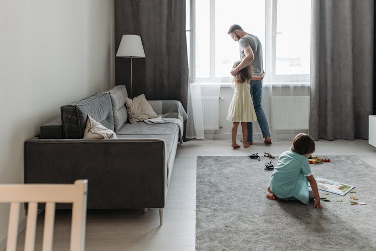 Father Relaxing With Children Playing At Home