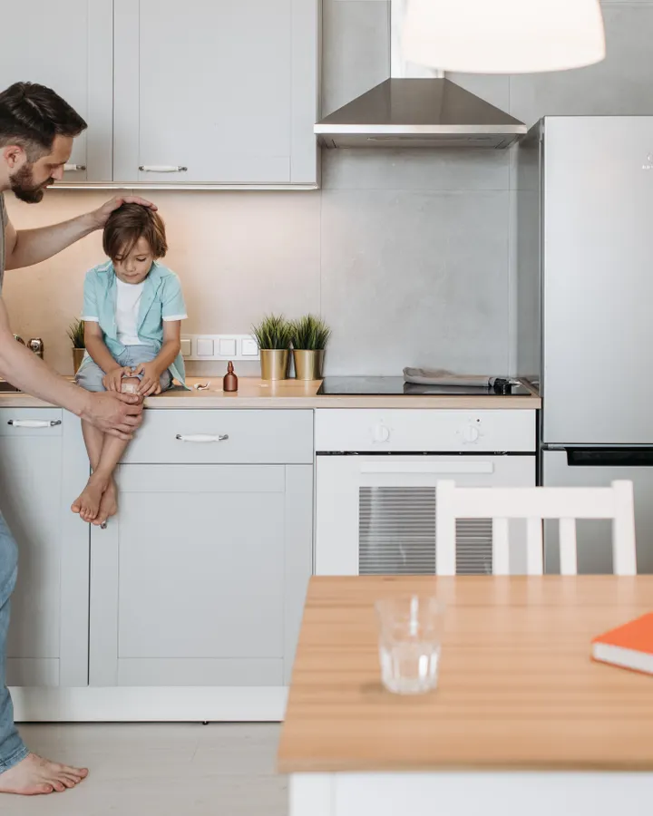 Bosch refrigerator repair in La Mesa, CA Father talking with his son on a kitchen counter in a modern kitchen, Bosch refrigerator repair in La Mesa