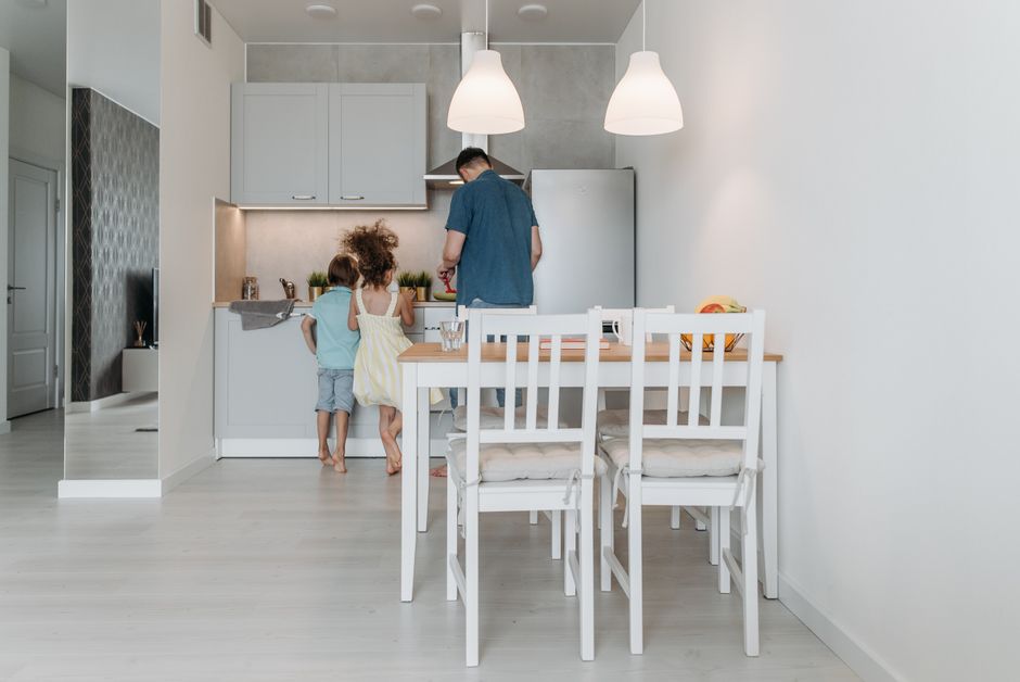 Father and children bonding over cooking in a contemporary kitchen setting.