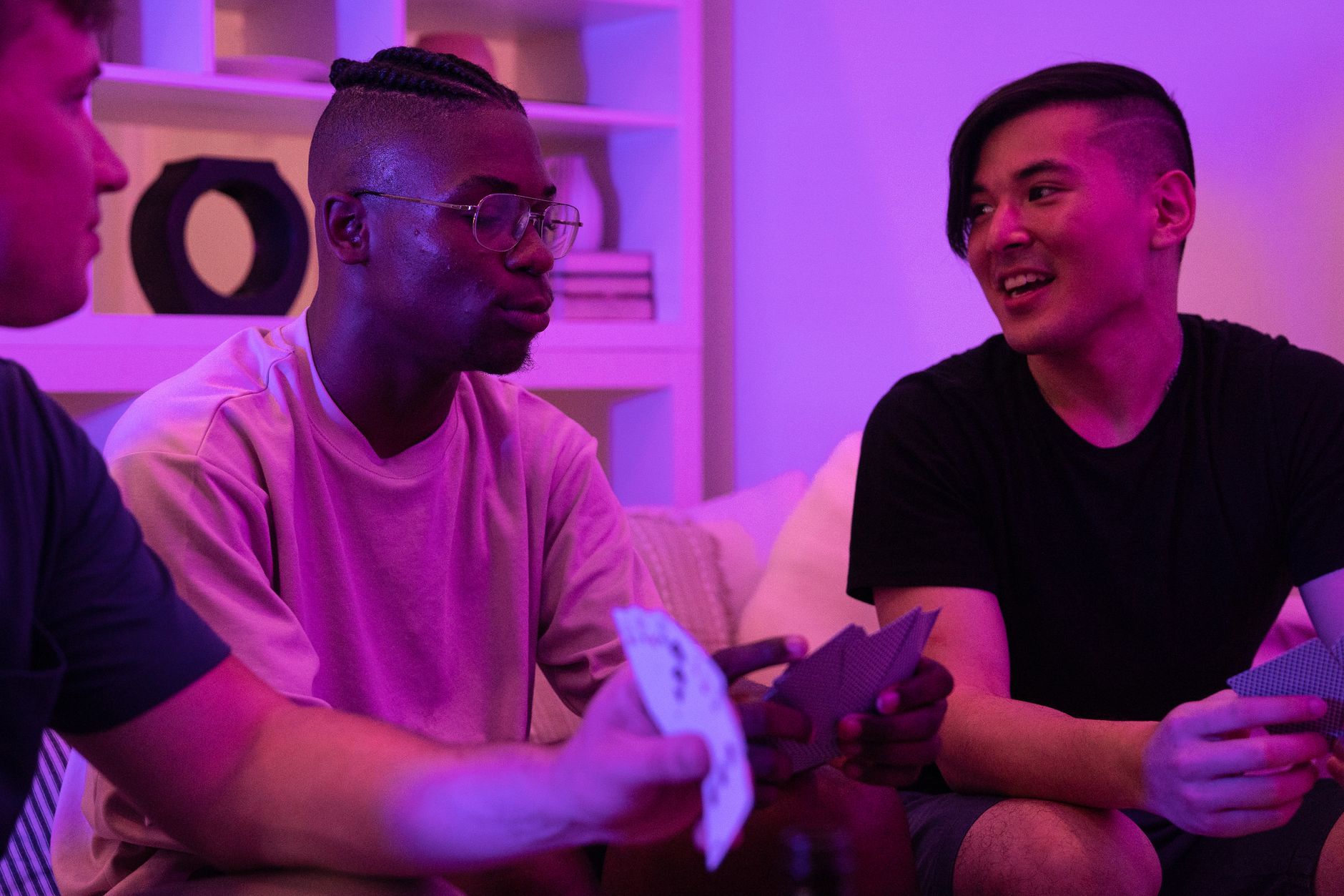 A group of diverse friends playing cards and enjoying a fun night indoors with mood lighting.