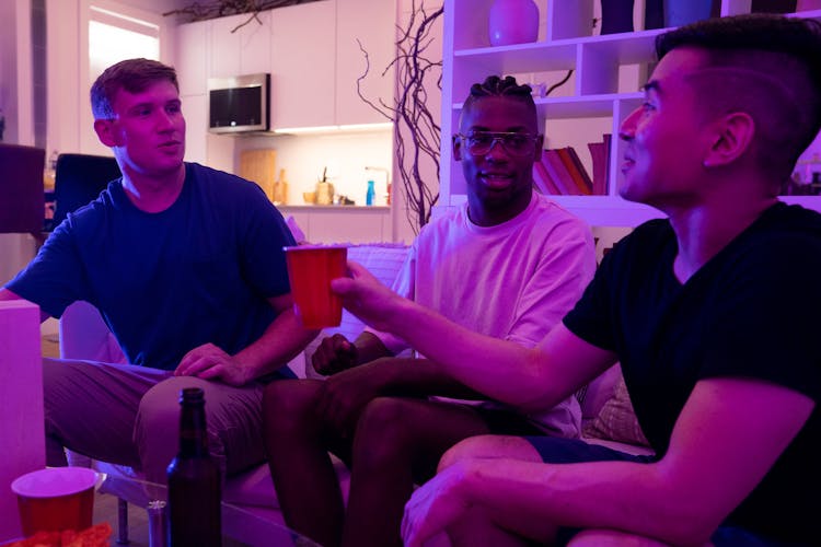 Men Sitting On A Couch Talking And Drinking Beer 