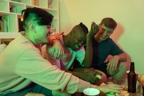 Free Three friends having fun playing a game at home, enjoying a relaxed and joyful evening together. Stock Photo