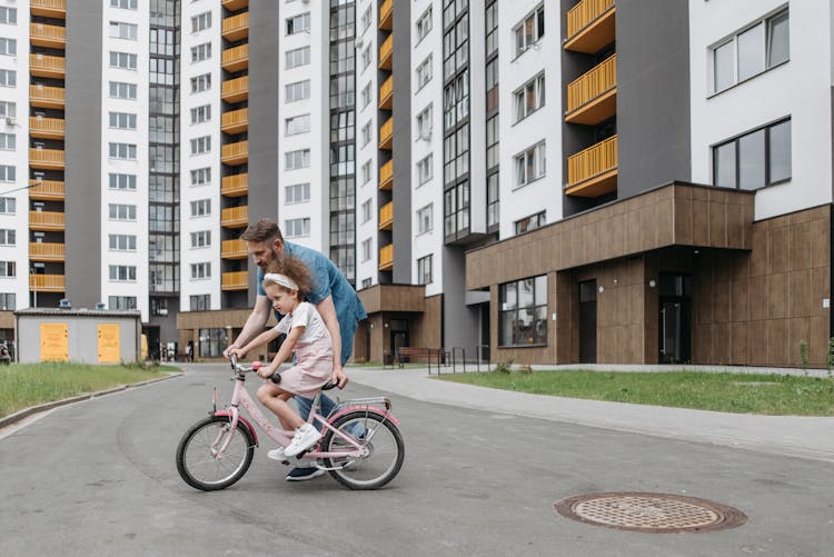 A Man Teaching His Daughter How To Ride A Bike