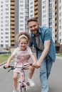 A Happy Daughter Riding a Bike while His Father is Guiding Her